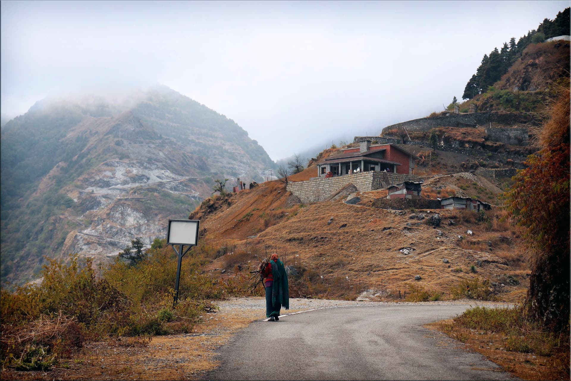 woman in the mountains carrying logs on her shoulder